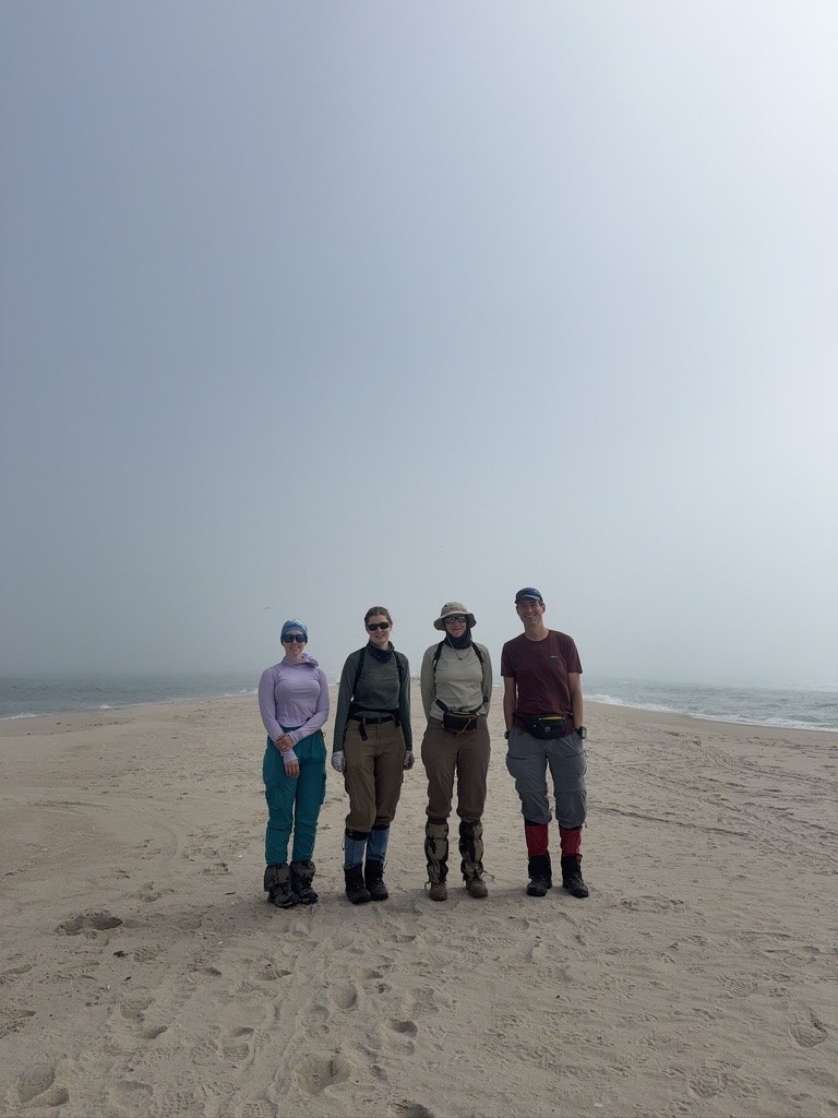 Victoria, Aurelia, Weronika and Jocelyn standing together at foggy East Point, with the beach and ocean behind them.